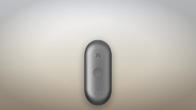 Plaud NotePin S in black seen from the front, standing on a neutral backdrop, with its round button and Plaud logo