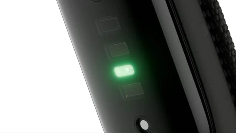 Close view of the underside of the Fitbit Air tracker with a green light glowing among its sensor windows