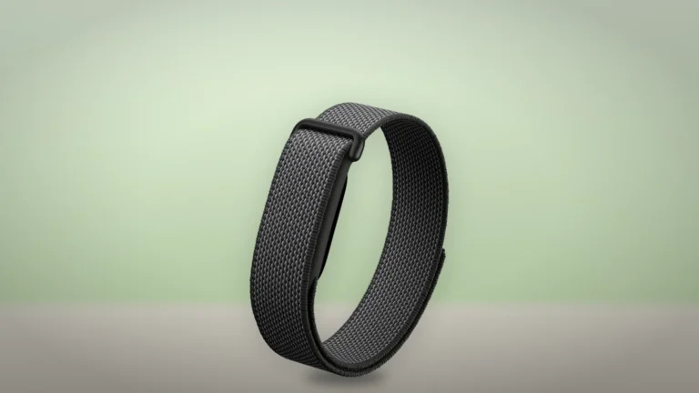 Black woven Fitbit Air band standing upright on a light surface in front of a soft green background