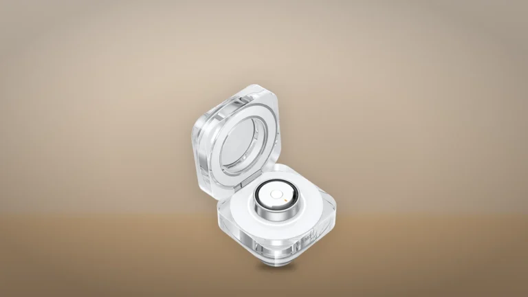 Galaxy Ring sitting in its open clear charging case on a warm beige backdrop